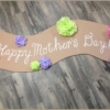 Mother's Day | Party | Cute Banner Idea | Mother's Day Decor | This easy to make banner adds a pretty festive look. Make it for Mother's Day or any other special holiday. It's cheap to make, too. Six Clever Sisters has an easy tutorial on making the banner as well as the tissue paper flowers.